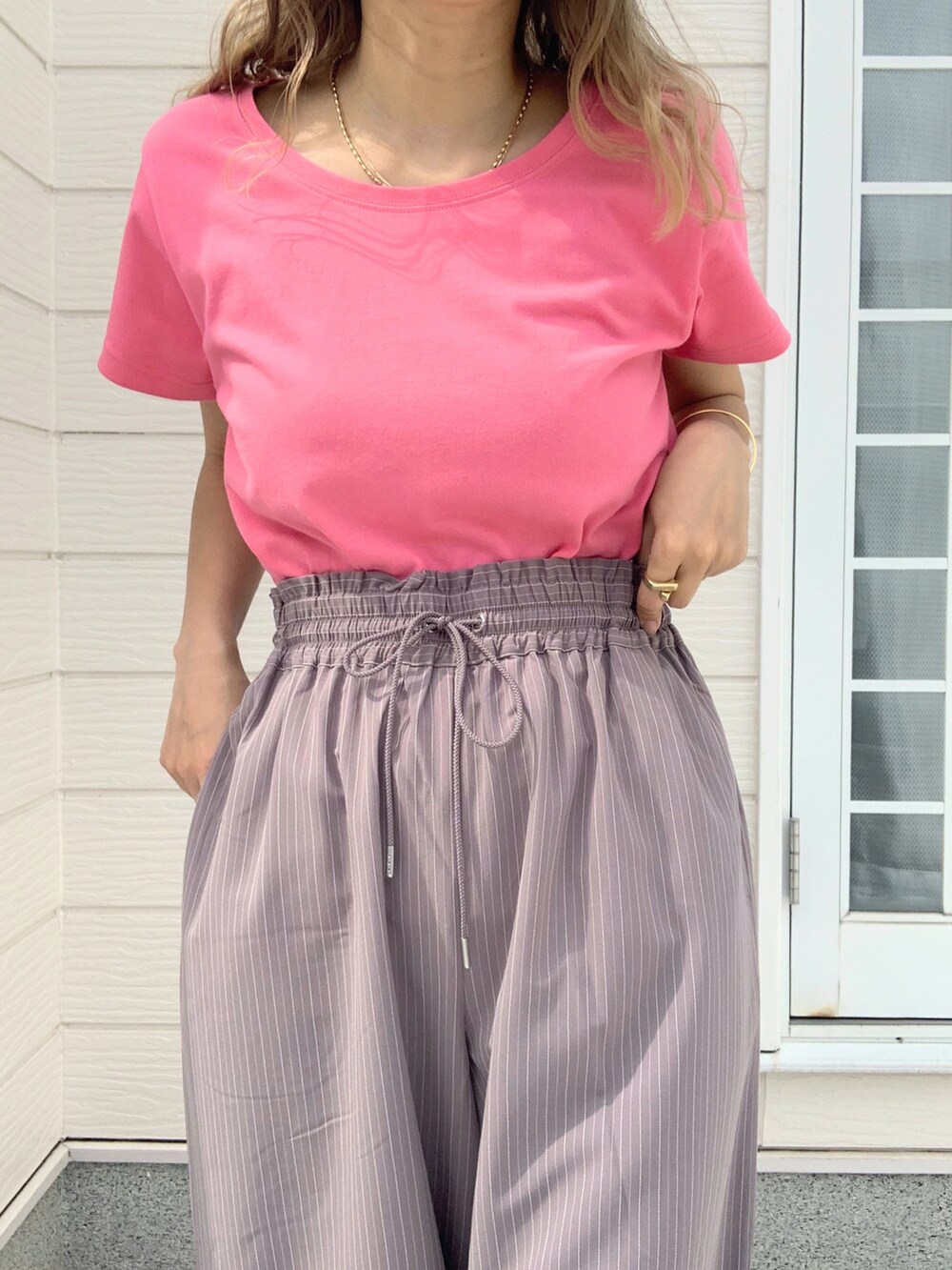 ピンク系のTシャツ/カットソー、グレー系のスラックス、ホワイト系のキャップを着用したレディースの春コーディネートの3枚目の写真