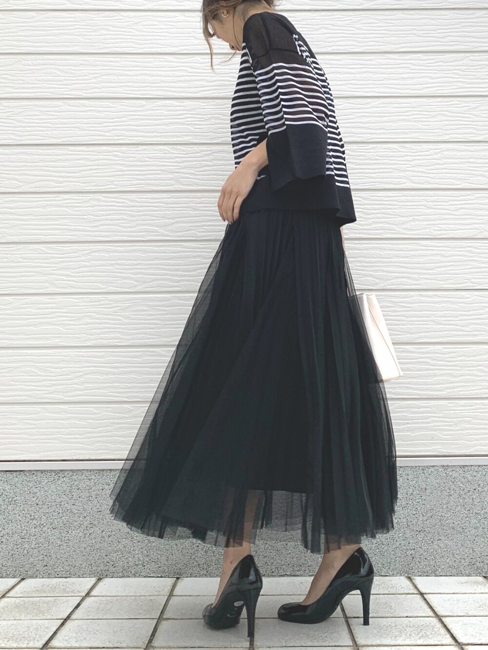 ホワイト系のハンドバッグ、ブラック系のニット/セーター、ブラック系のスカートを着用したレディースの春コーディネートの2枚目の写真