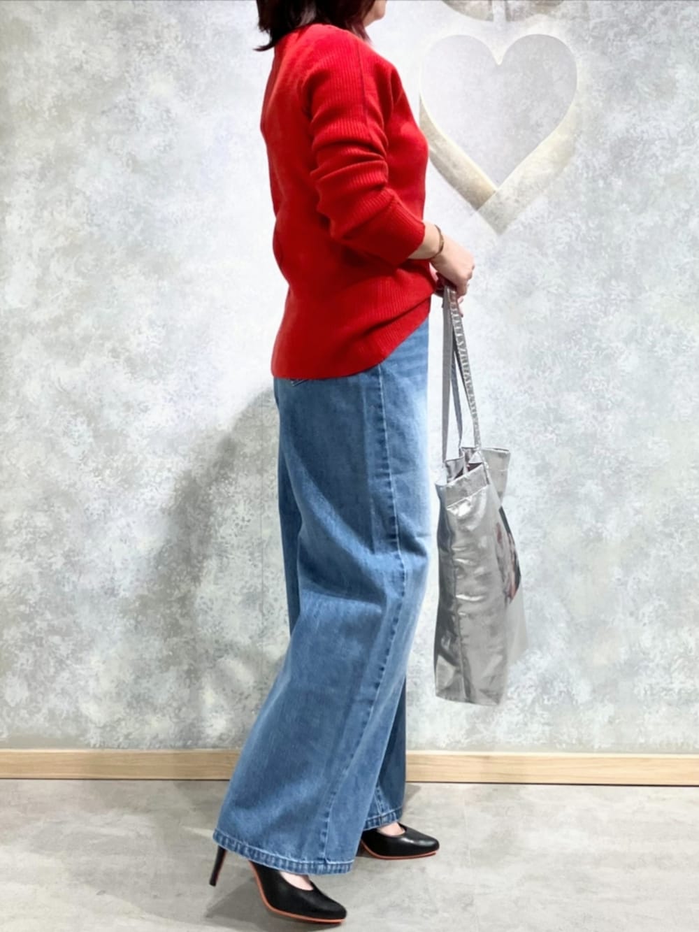シルバー系のトートバッグ、ブルー系のデニムパンツ、レッド系のニット/セーターを着用したレディースの秋コーディネートの3枚目の写真