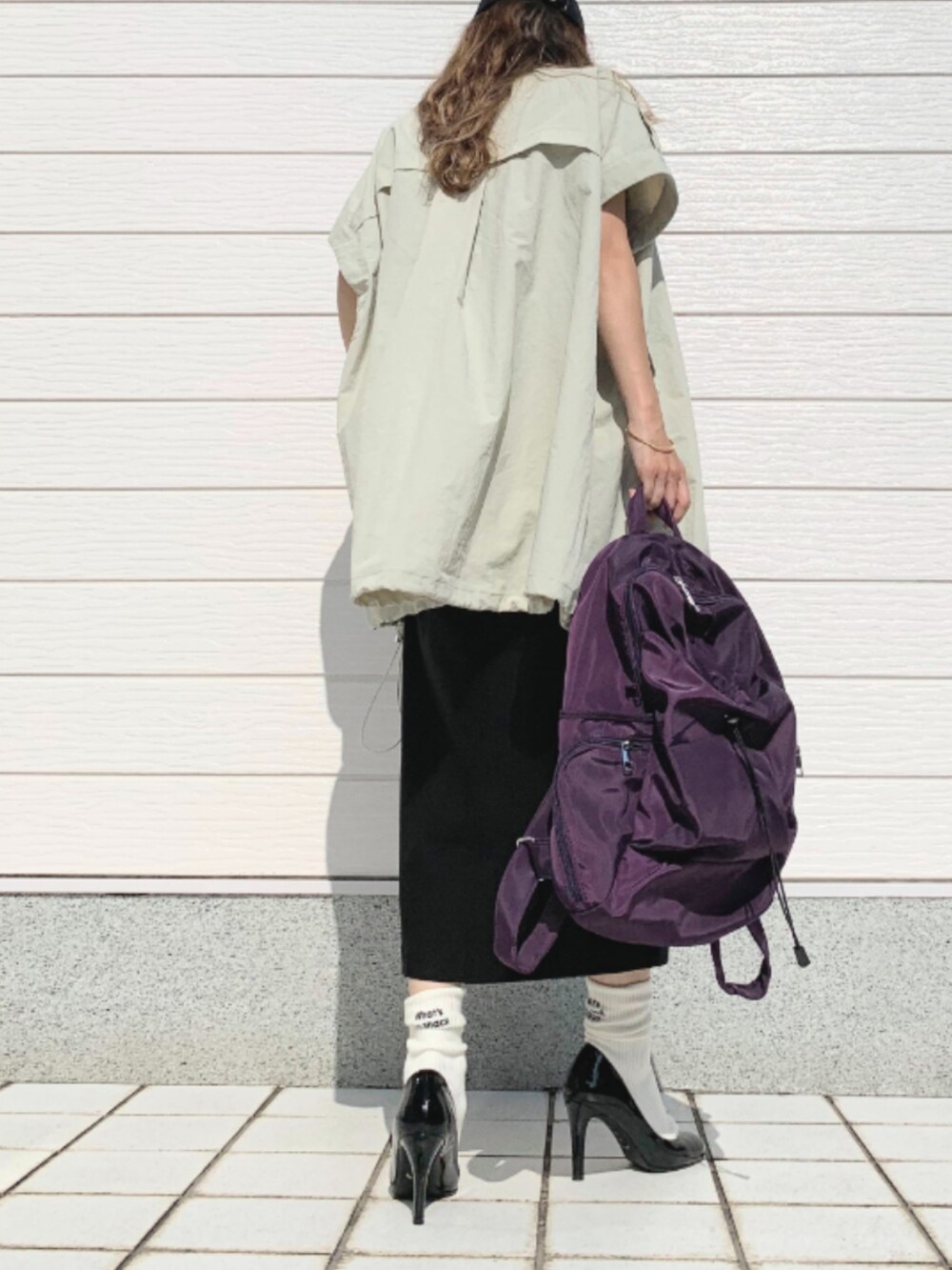 グレー系のTシャツ/カットソー、ブラック系のスカート、パープル系のバックパック/リュックを着用したレディースの夏コーディネートの3枚目の写真