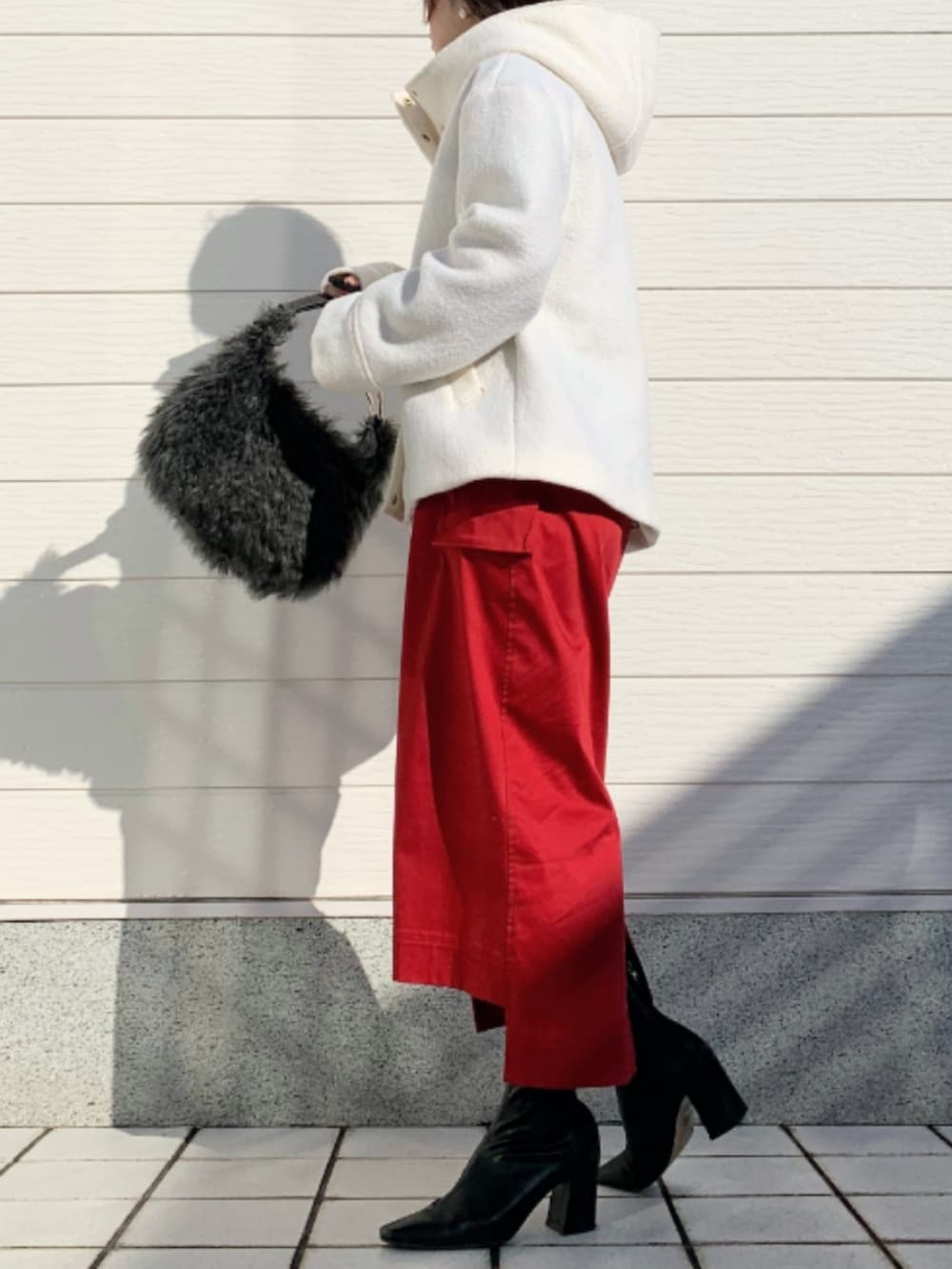 グレー系のハンドバッグ、レッド系のスカート、ブラック系のTシャツ/カットソーを着用したレディースの秋コーディネートの2枚目の写真