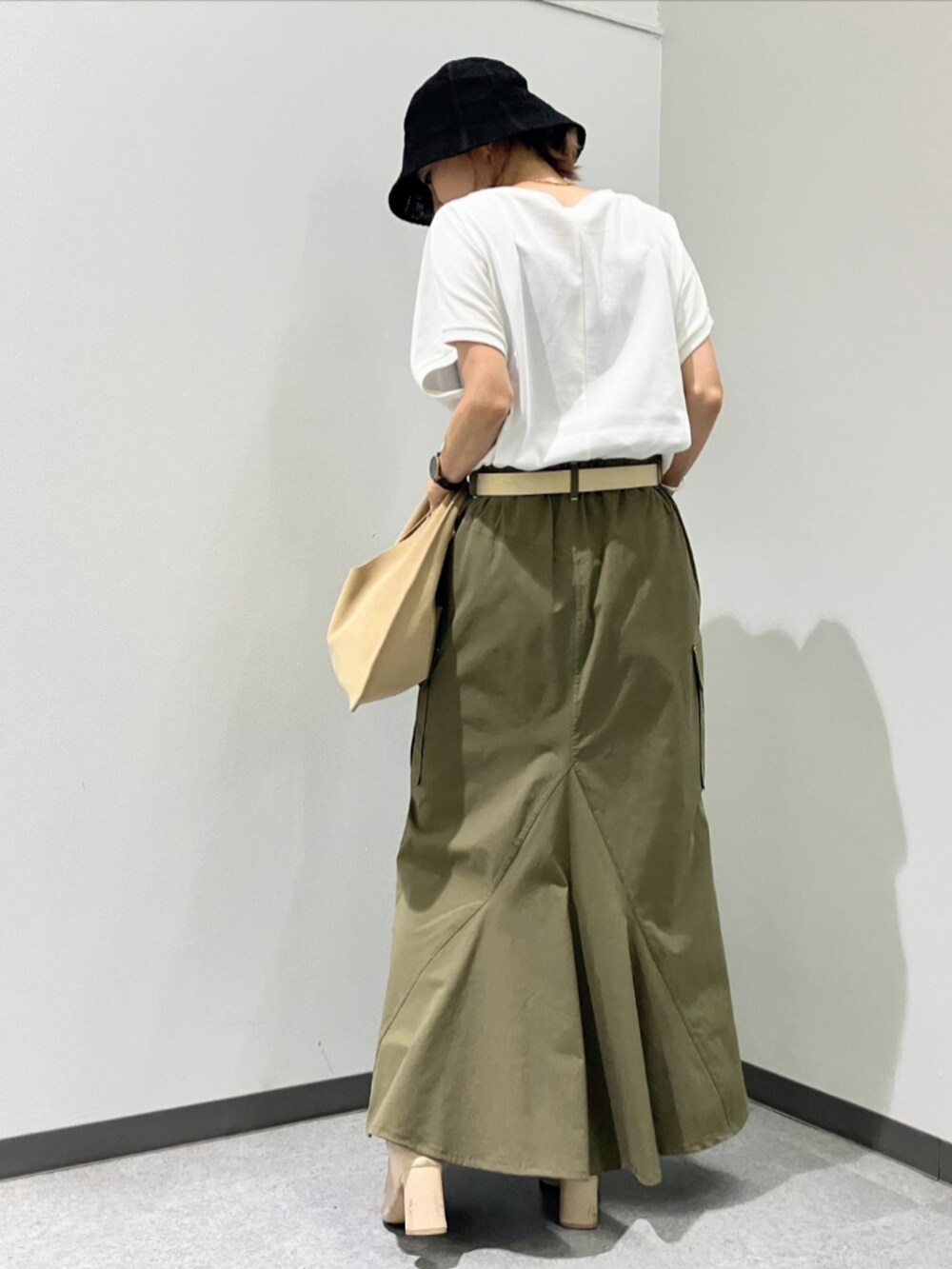 グリーン系のスカート、ベージュ系のトートバッグ、ホワイト系のTシャツ/カットソーを着用したレディースの夏コーディネートの2枚目の写真