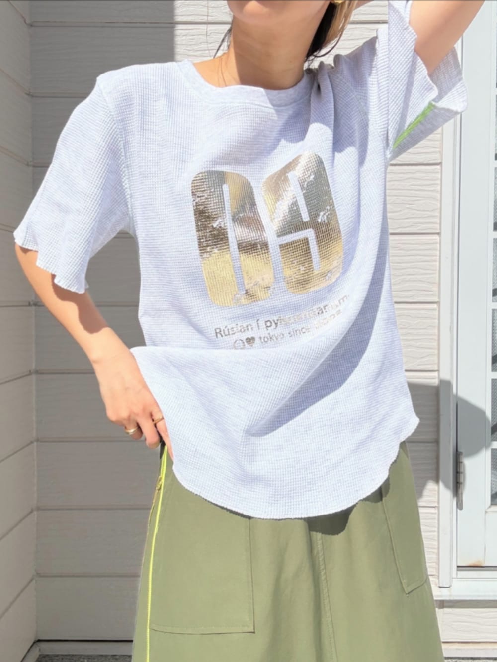 グリーン系のスカート、グレー系のTシャツ/カットソー、ブラック系のキャップを着用したレディースの春コーディネートの4枚目の写真