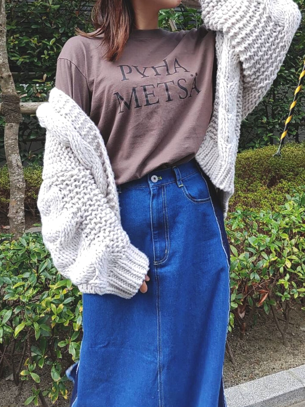 グレー系のTシャツ/カットソー、ブルー系のデニムスカート、ホワイト系のスニーカーを着用したレディースの秋コーディネートの4枚目の写真