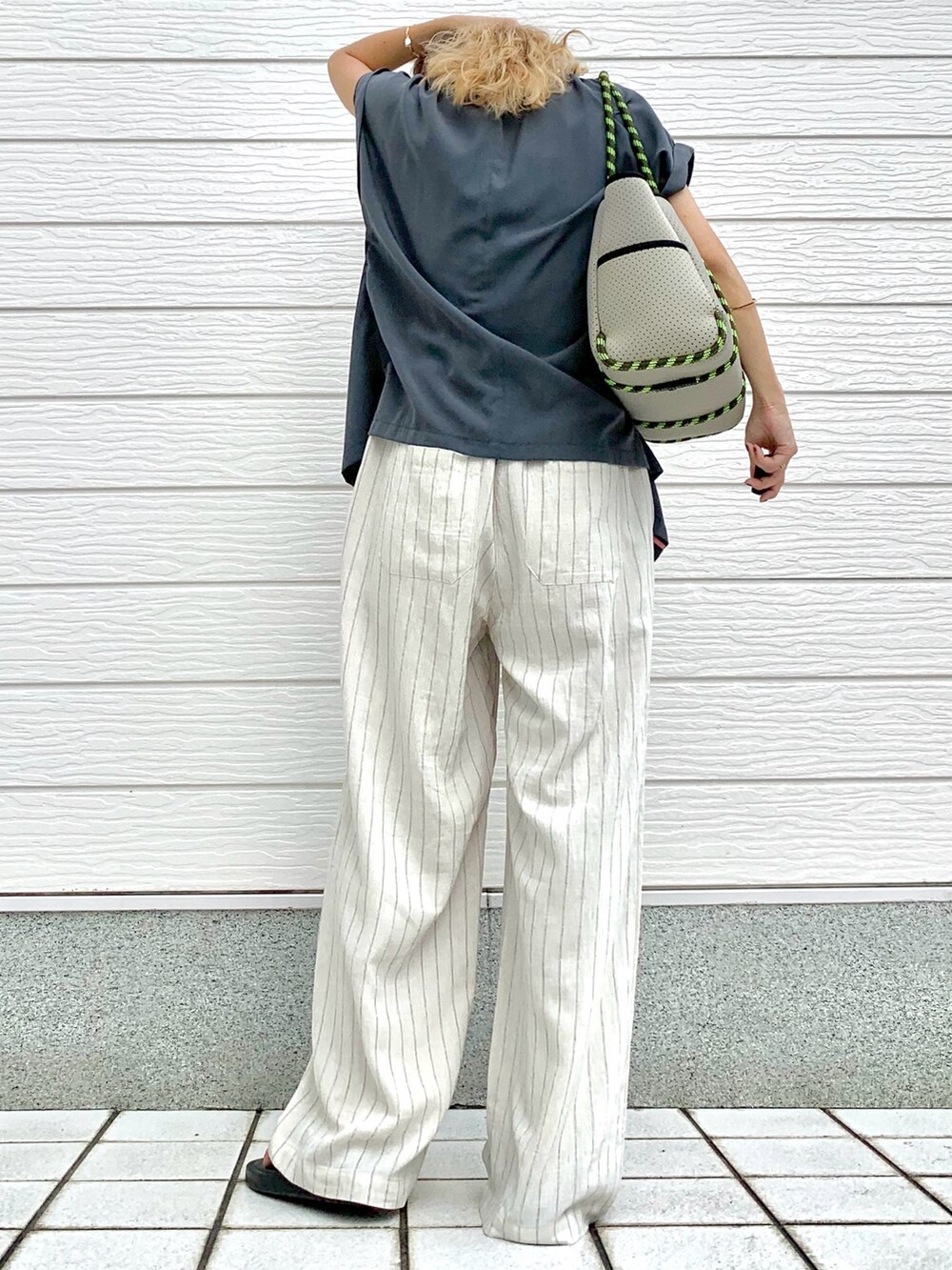 グレー系のトートバッグ、グレー系のテーラードジャケット、ホワイト系のその他パンツを着用したレディースの夏コーディネートの3枚目の写真