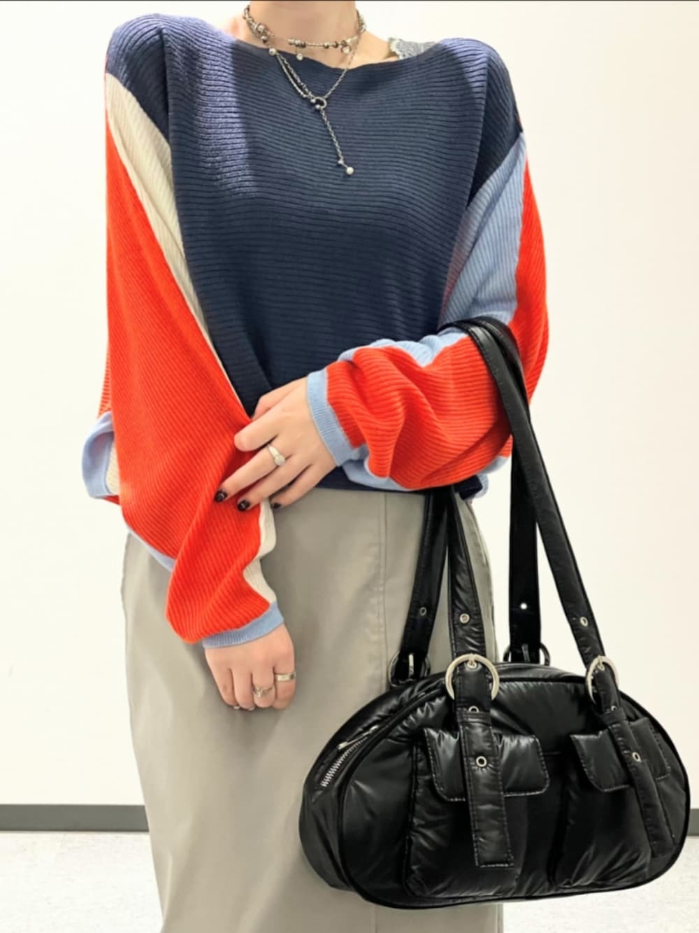 オレンジ系のニット/セーター、グレー系のスカート、ブラック系のボストンバッグを着用したレディースの秋コーディネートの4枚目の写真