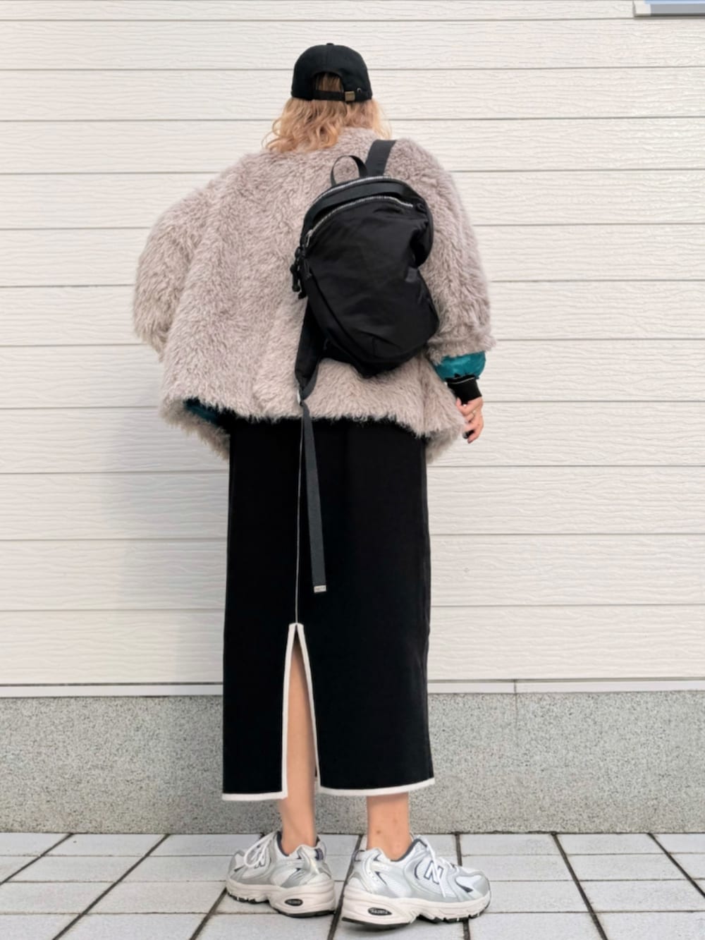 シルバー系のスニーカー、ブラック系のワンピース、ブラック系のバックパック/リュックを着用したレディースの秋コーディネートの3枚目の写真