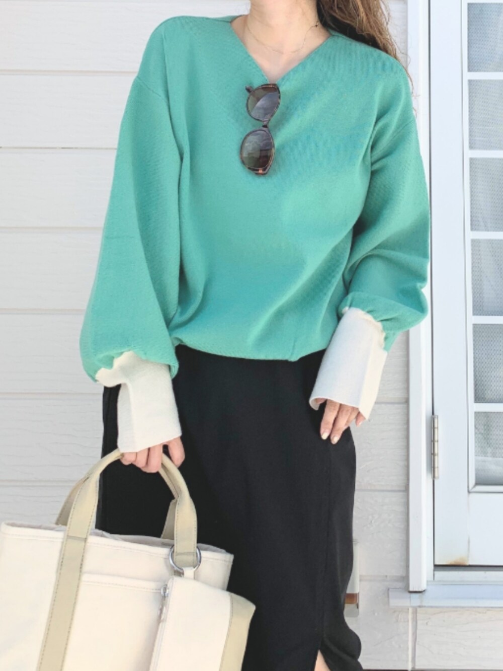 ベージュ系のトートバッグ、ブラック系のスカート、グリーン系のニット/セーターを着用したレディースの夏コーディネートの4枚目の写真