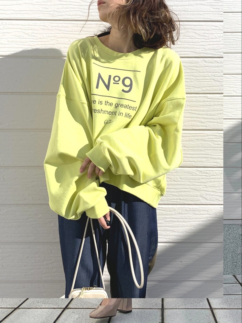 グリーン系のデニムパンツ、ホワイト系のショルダーバッグ、イエロー系のスウェットを着用したレディースの冬コーディネートの4枚目の写真