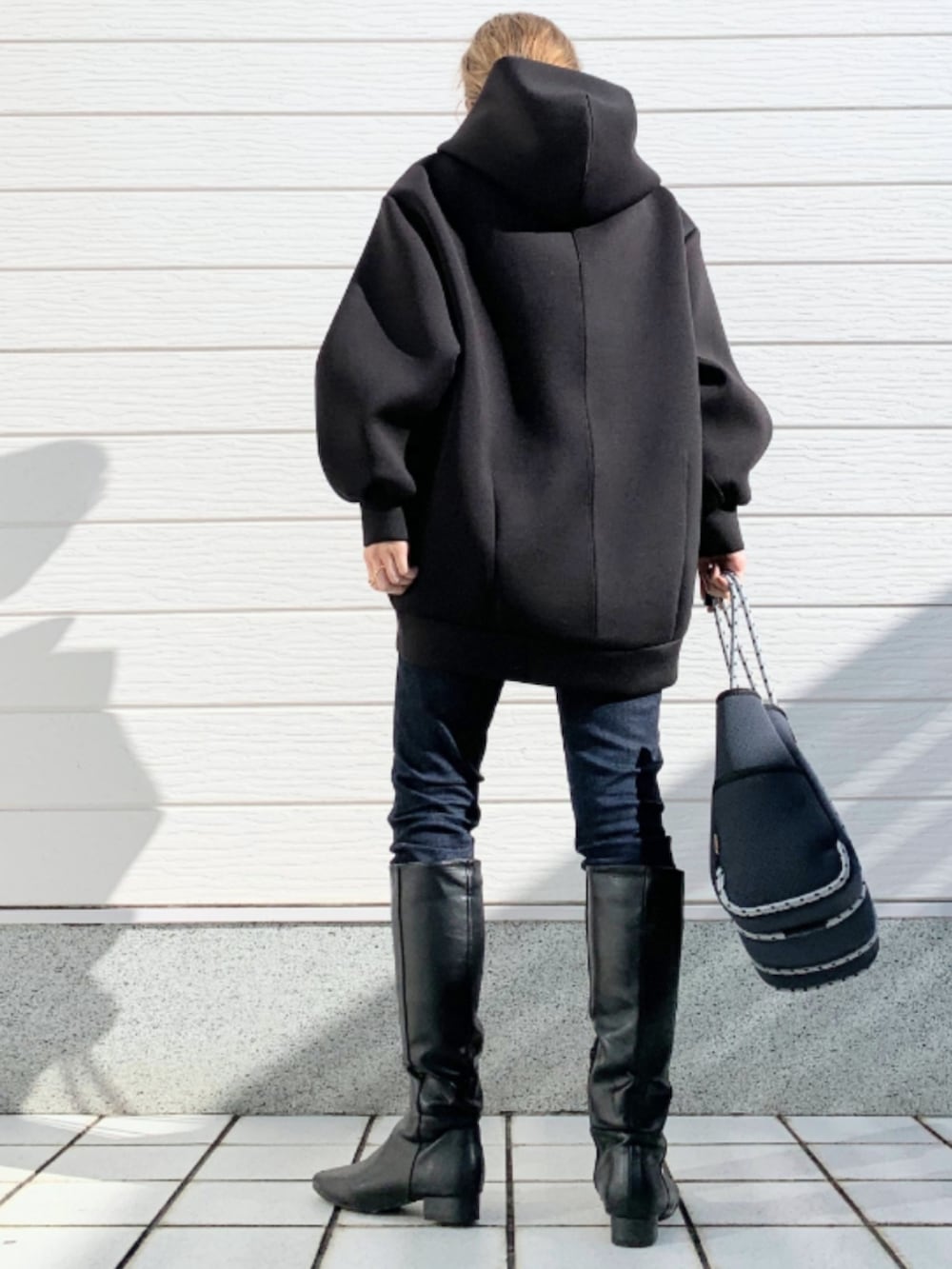 ブラック系のブーツ、ブルー系のデニムパンツ、ブルー系のトートバッグを着用したレディースの秋コーディネートの3枚目の写真