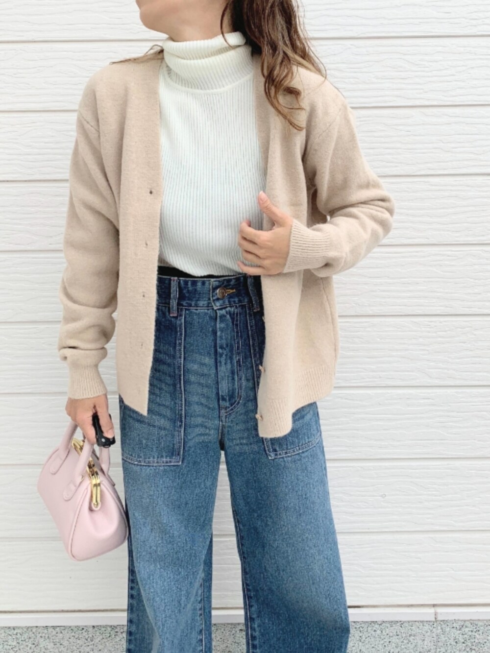 ブルー系のデニムパンツ、ピンク系のショルダーバッグ、ホワイト系のカーディガン/ボレロを着用したレディースの秋コーディネートの3枚目の写真