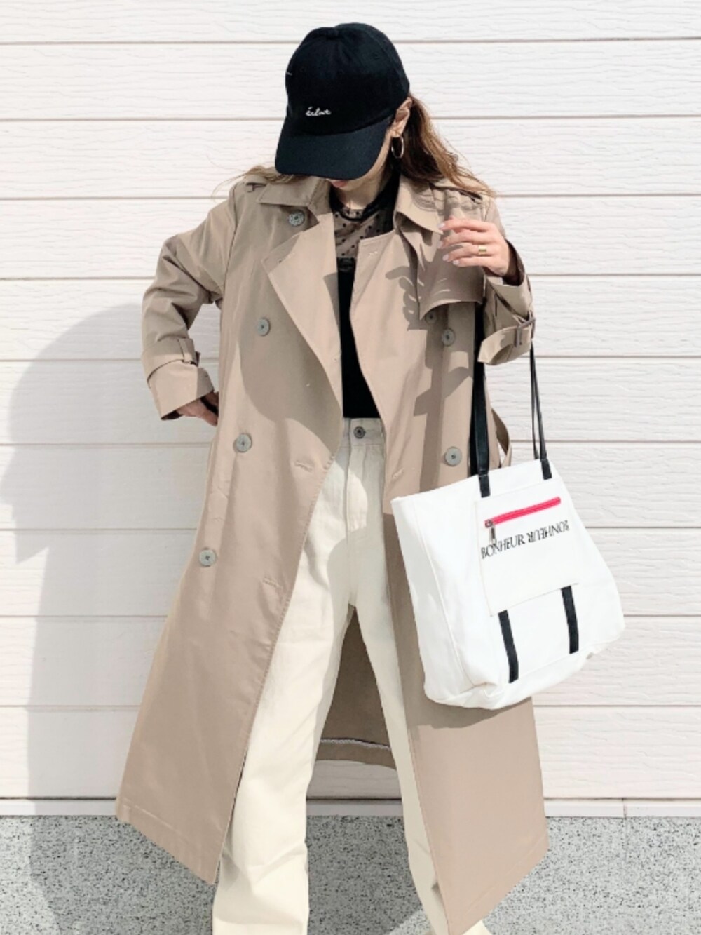 ホワイト系のトートバッグ、ベージュ系のトレンチコート、ブラック系のTシャツ/カットソーを着用したレディースの冬コーディネートの4枚目の写真