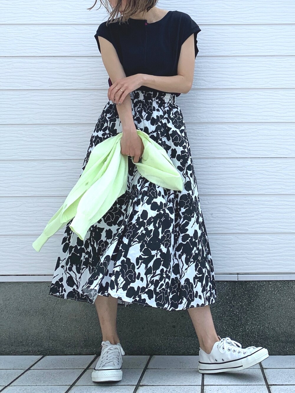 ホワイト系のスニーカー、ブラック系のスカート、ブラック系のTシャツ/カットソーを着用したレディースの春コーディネートの2枚目の写真