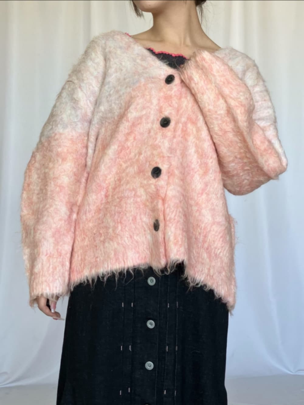 ブラック系のデニムスカート、シルバー系のスニーカー、ピンク系のカーディガン/ボレロを着用したレディースの冬コーディネートの3枚目の写真