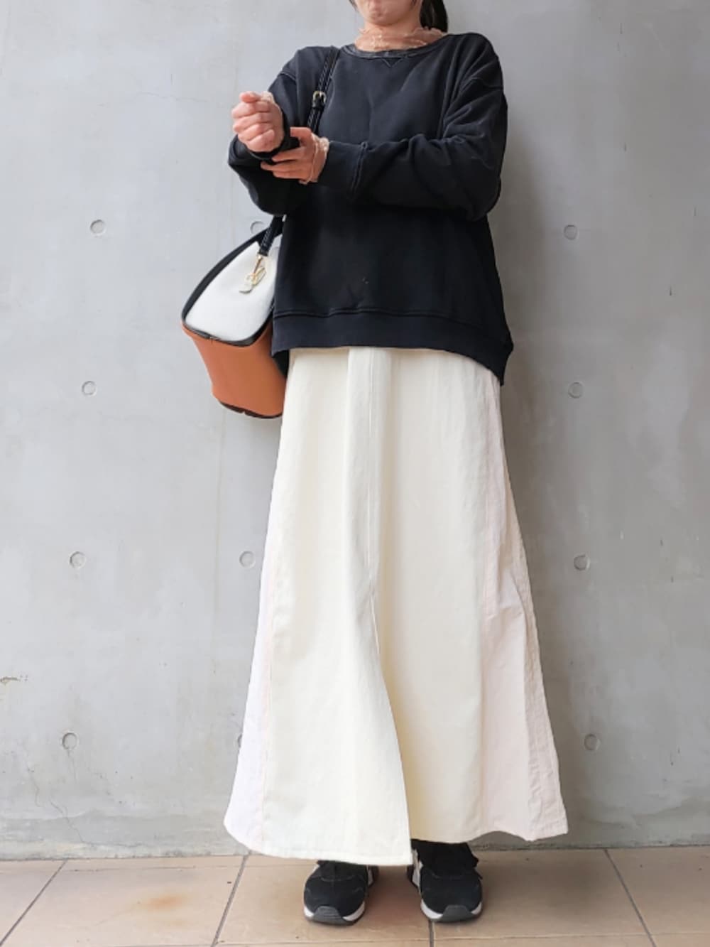 ブラック系のスウェット、ホワイト系のデニムスカート、ブラック系のスニーカーを着用したレディースの冬コーディネートの3枚目の写真