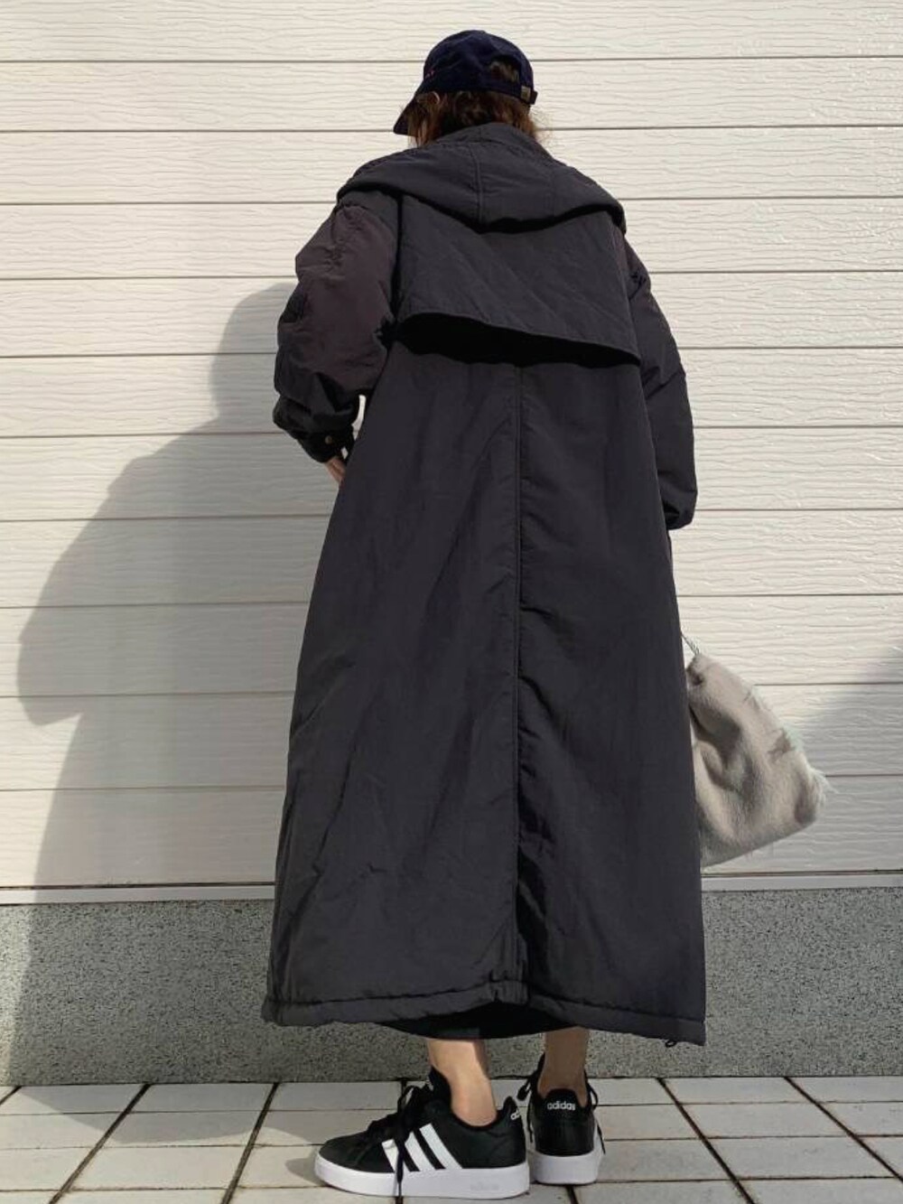 グレー系のクラッチバッグ、ブラック系のスニーカー、ブルー系のスカートを着用したレディースの秋コーディネートの3枚目の写真