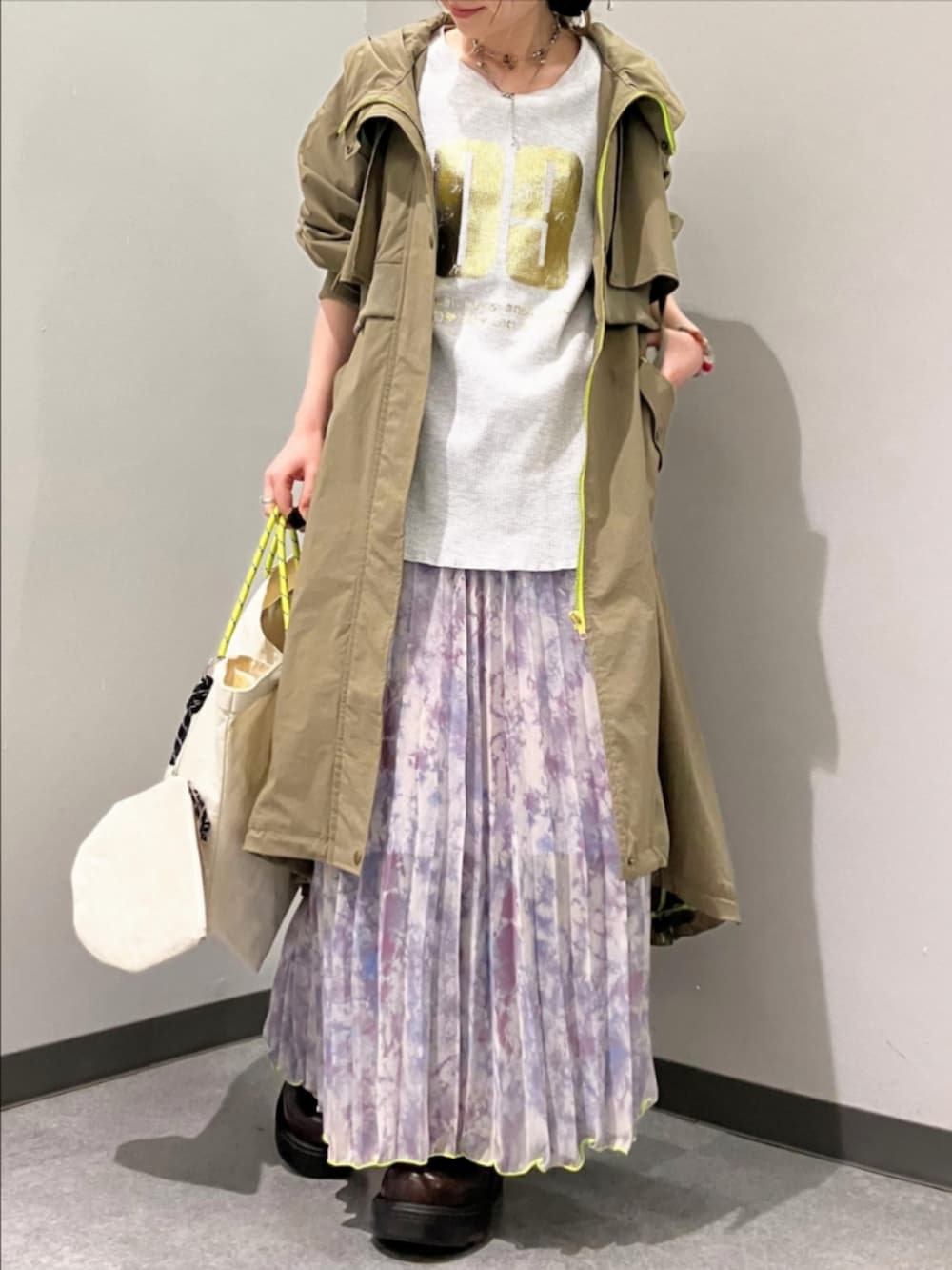 グリーン系のミリタリージャケット、グレー系のTシャツ/カットソー、ホワイト系のトートバッグを着用したレディースの春コーディネートの2枚目の写真