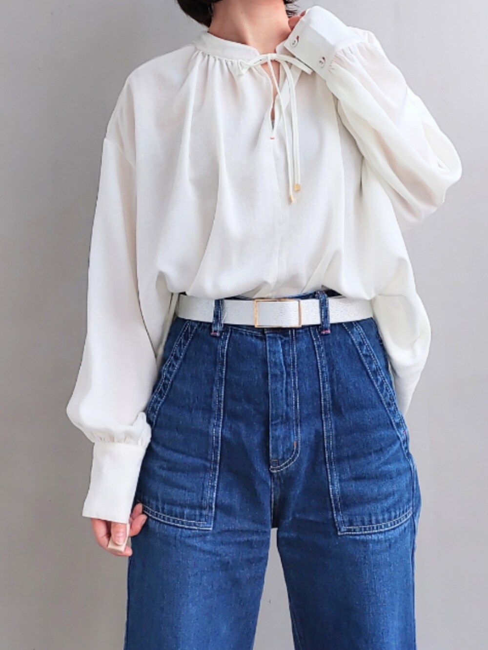 ブルー系のデニムパンツ、ホワイト系のスニーカー、ブラック系のニット/セーターを着用したレディースの秋コーディネートの4枚目の写真