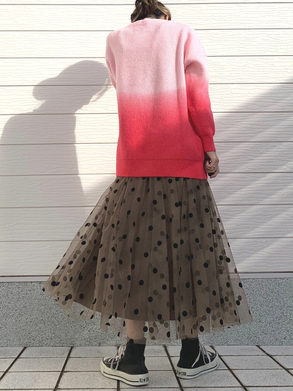 ピンク系のニット/セーター、ブラウン系のスカート、ブラック系のスニーカーを着用したレディースの冬コーディネートの3枚目の写真