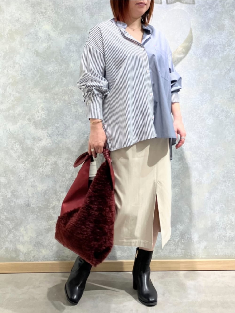 レッド系のトートバッグ、ベージュ系のスカート、ブルー系のシャツ/ブラウスを着用したレディースの冬コーディネートの2枚目の写真