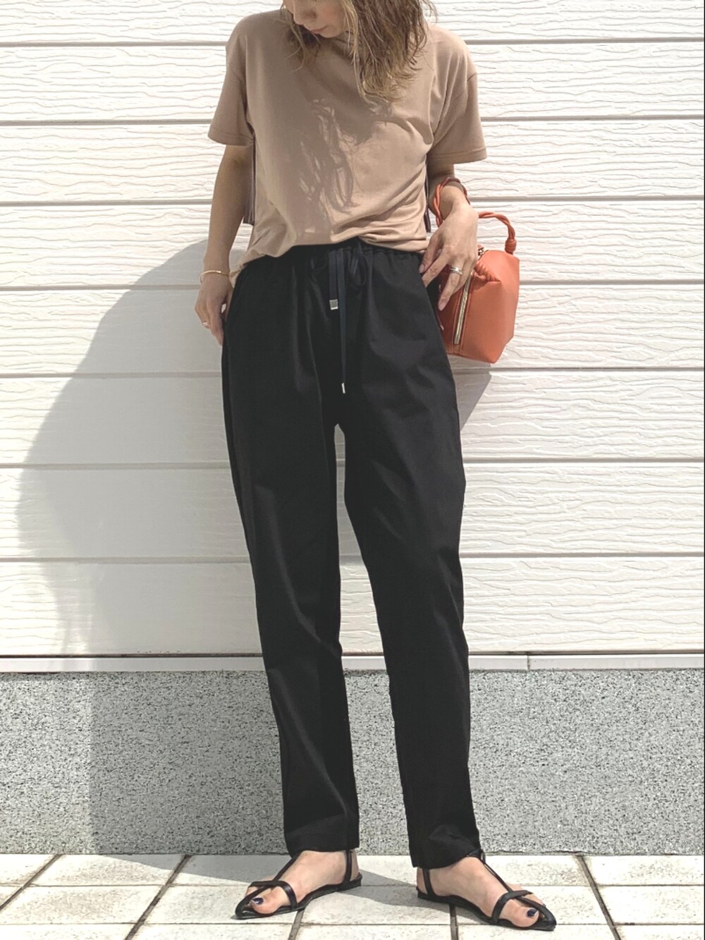 ブラック系のその他パンツ、ベージュ系のTシャツ/カットソー、オレンジ系のハンドバッグを着用したレディースの春コーディネートの3枚目の写真