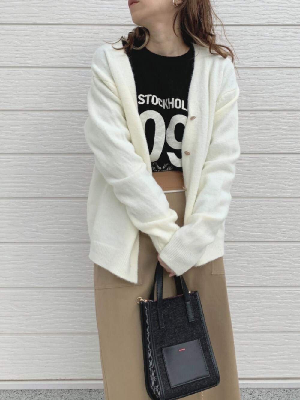 ブラック系のショルダーバッグ、ベージュ系のスカート、ブラック系のTシャツ/カットソーを着用したレディースの秋コーディネートの2枚目の写真