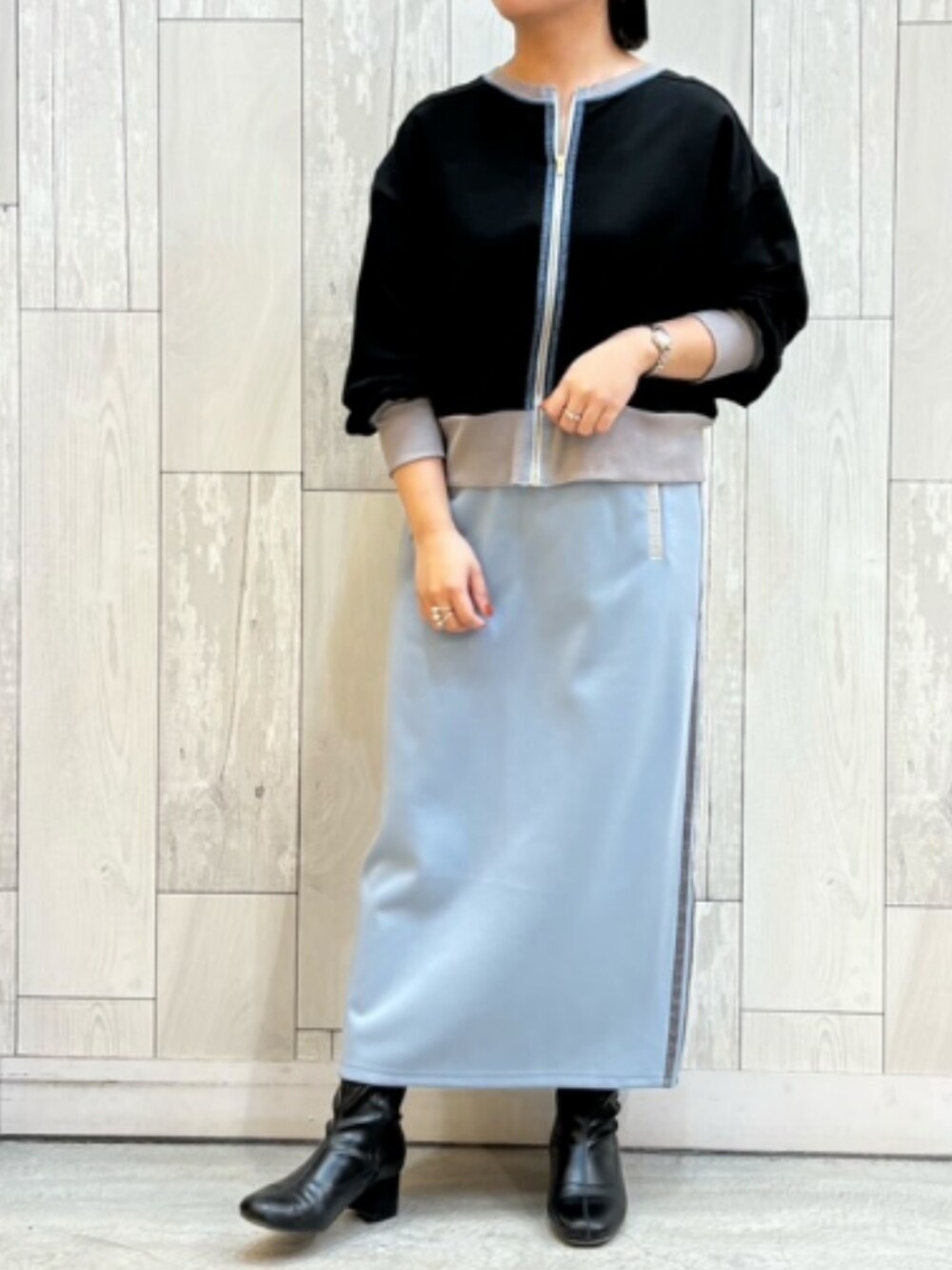 ブルー系のスカート、ブラック系のカーディガン/ボレロ、ホワイト系のキャップを着用したレディースの冬コーディネートの2枚目の写真