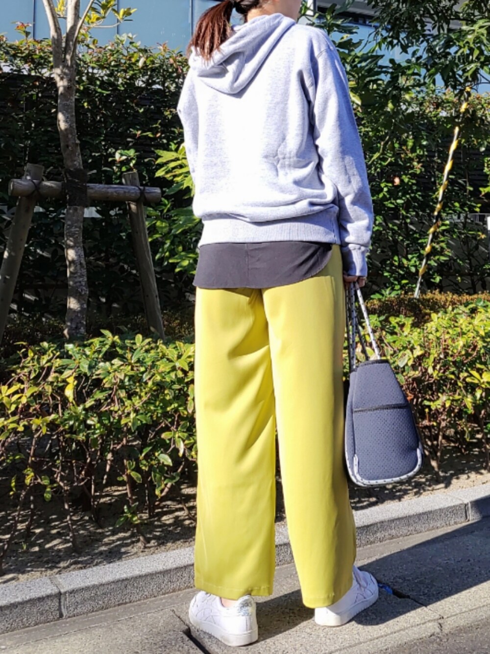 ブルー系のトートバッグ、グリーン系のスラックス、ホワイト系のスニーカーを着用したレディースの冬コーディネートの3枚目の写真