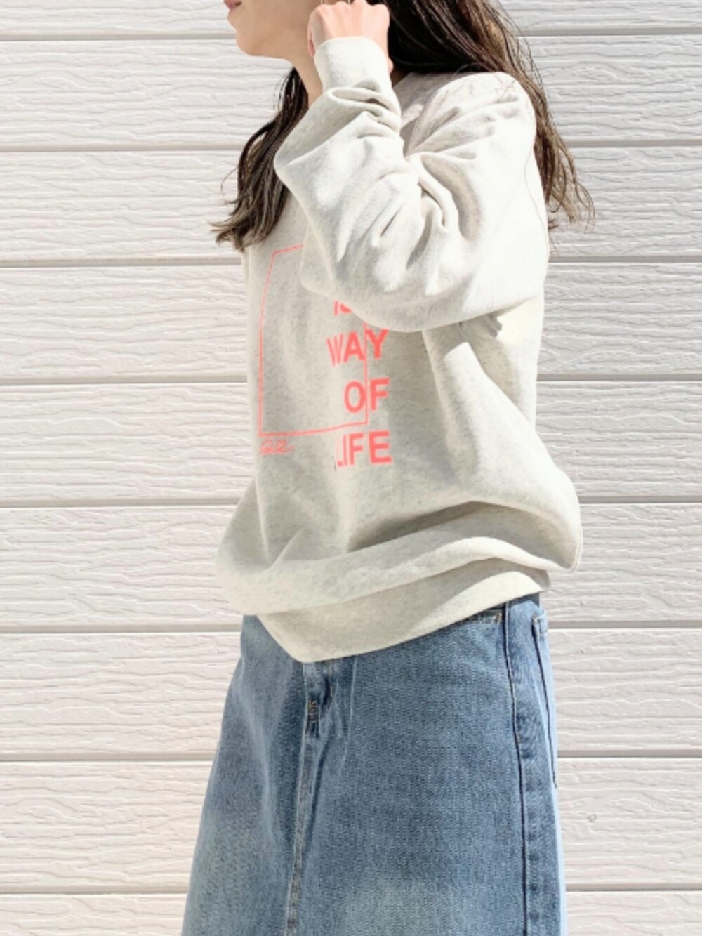 ベージュ系のスウェット、ブルー系のデニムスカート、ホワイト系のスニーカーを着用したレディースの春コーディネートの5枚目の写真