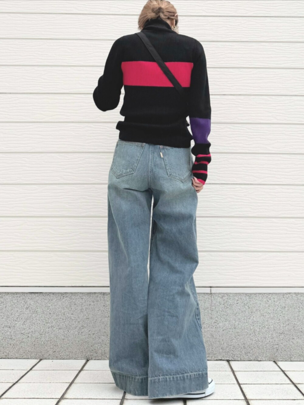 ブルー系のデニムパンツ、ブラック系のショルダーバッグ、ブラック系のスニーカーを着用したレディースの秋コーディネートの2枚目の写真