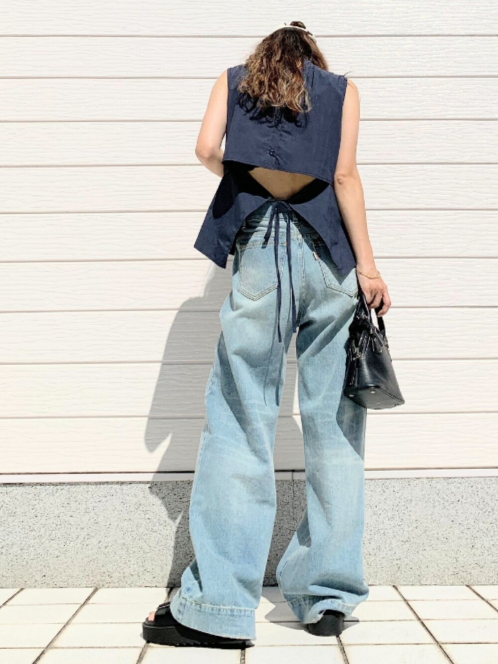 ブルー系のデニムパンツ、ブラック系のサンダル、ブルー系のシャツ/ブラウスを着用したレディースの夏コーディネートの3枚目の写真