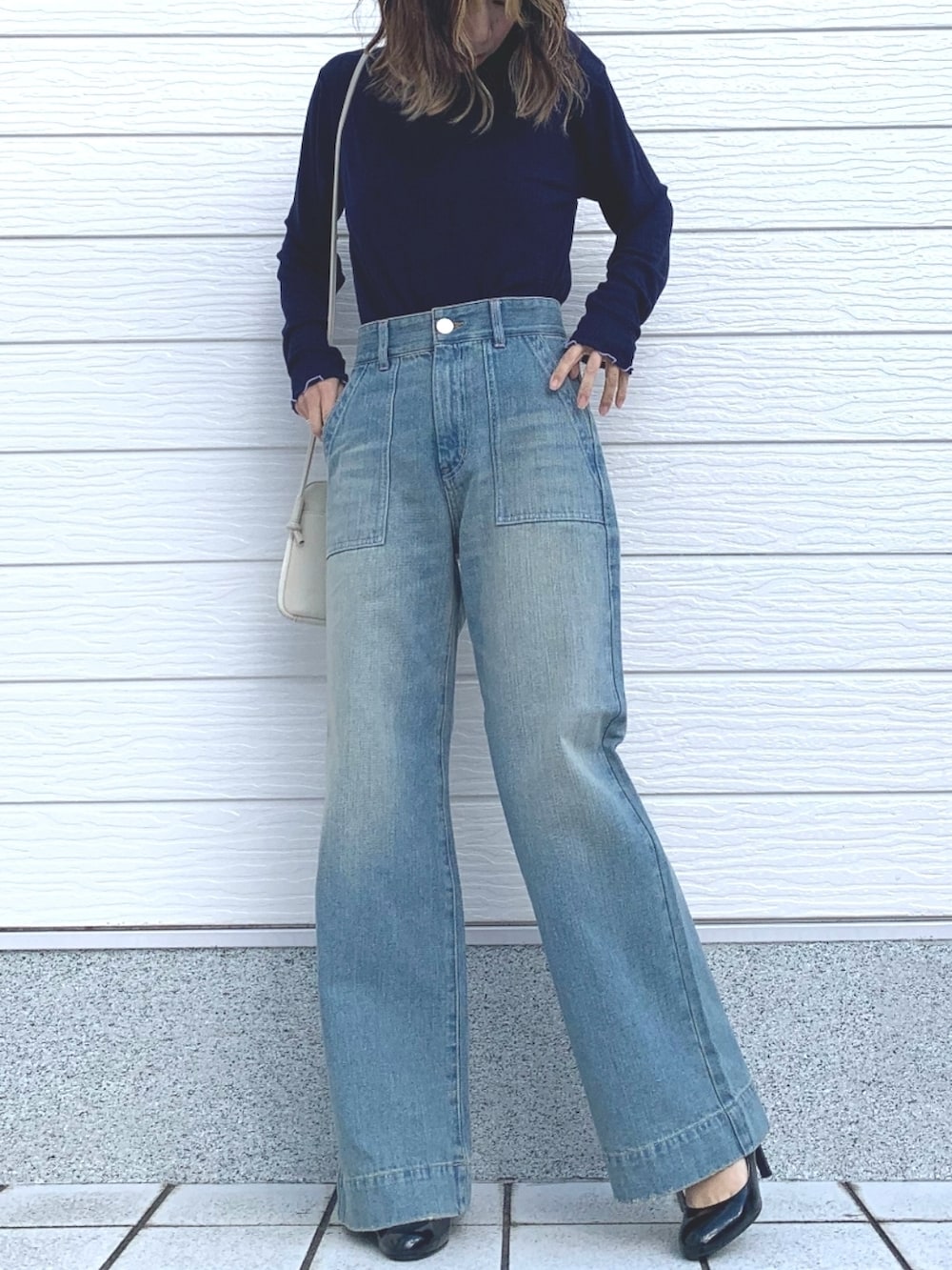 ホワイト系のショルダーバッグ、ブルー系のTシャツ/カットソー、ブルー系のデニムパンツを着用したレディースの冬コーディネートの2枚目の写真