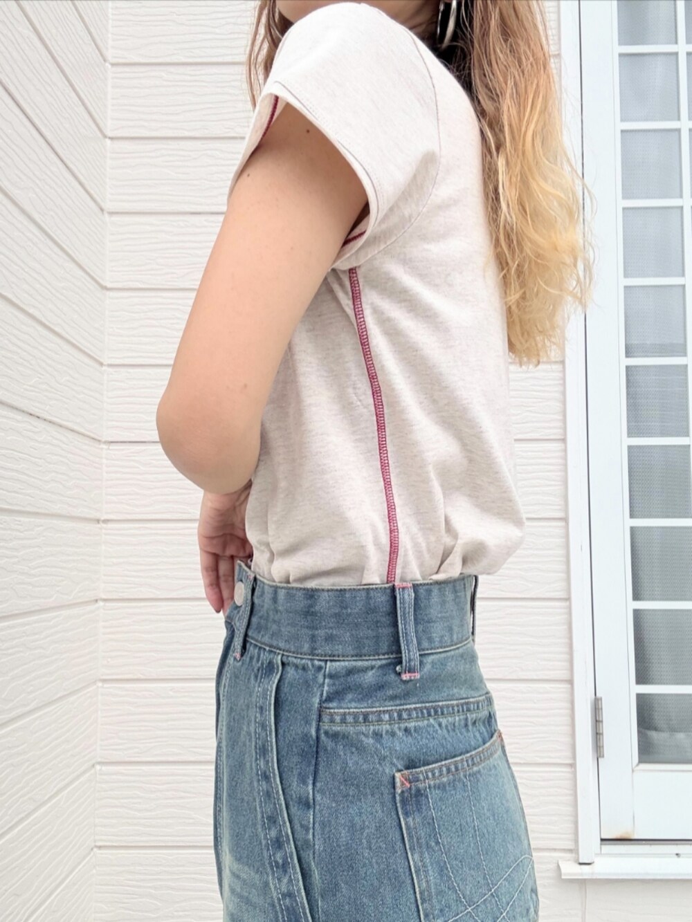 ブルー系のデニムパンツ、ベージュ系のハンドバッグ、ホワイト系のTシャツ/カットソーを着用したレディースの夏コーディネートの4枚目の写真