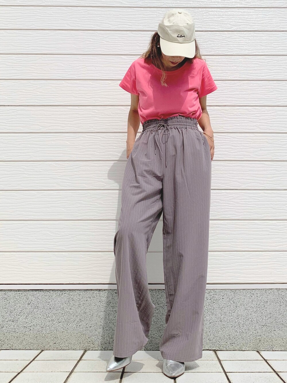 ピンク系のTシャツ/カットソー、グレー系のスラックス、ホワイト系のキャップを着用したレディースの春コーディネートの2枚目の写真