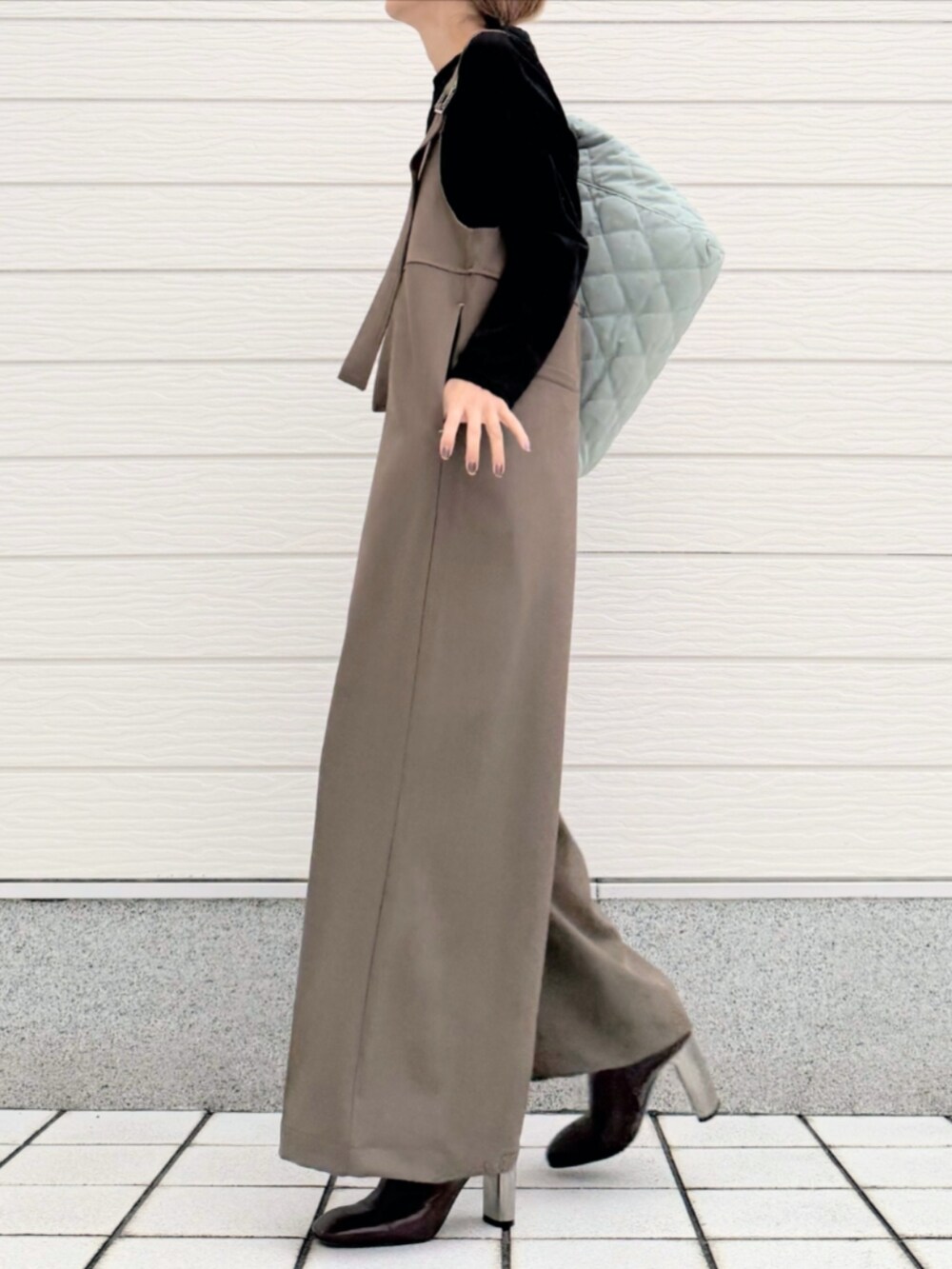 グリーン系のトートバッグ、ブラック系のTシャツ/カットソー、ブラウン系のブーツを着用したレディースの秋コーディネートの2枚目の写真