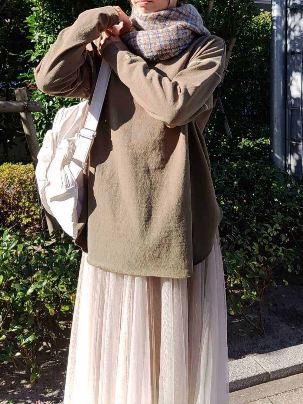 グリーン系のTシャツ/カットソー、ホワイト系のバックパック/リュック、ゴールド系のスカートを着用したレディースの秋コーディネートの3枚目の写真