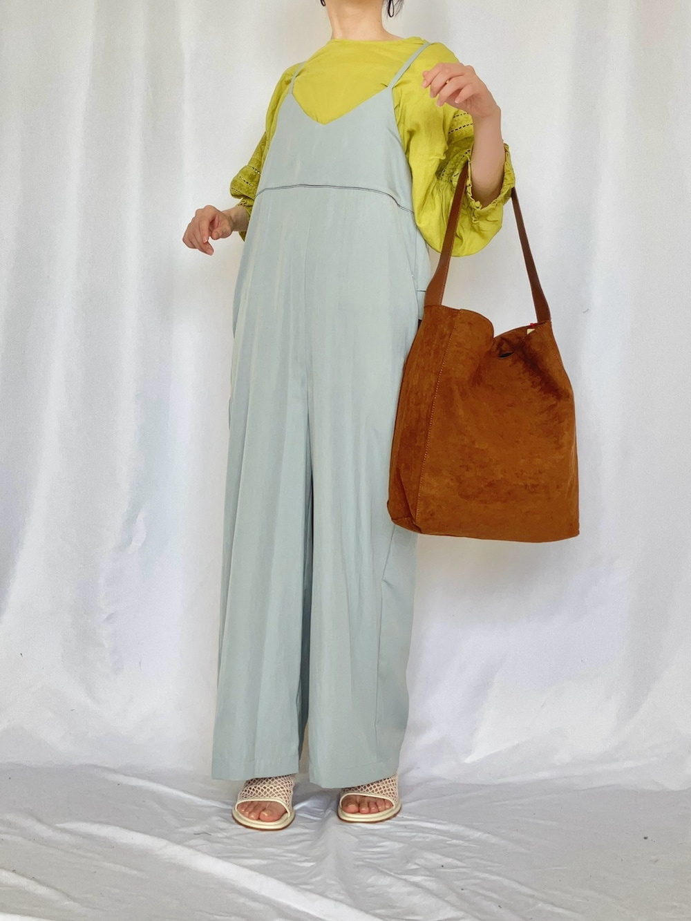 イエロー系のトートバッグ、ブルー系のサロペット/オーバーオール、グレー系のサンダルを着用したレディースの夏コーディネートの2枚目の写真