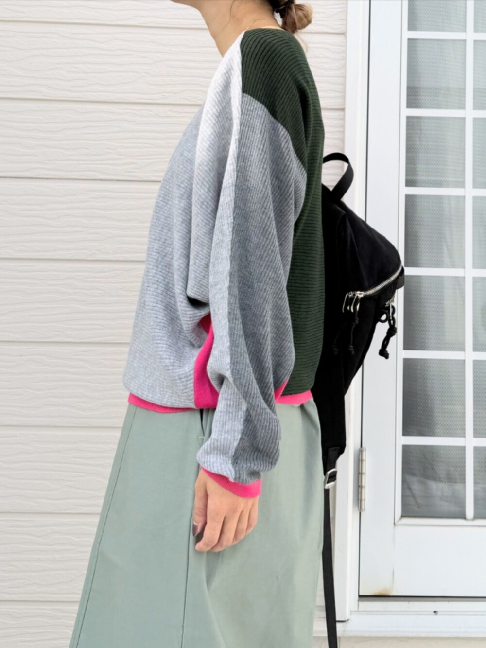 グリーン系のスカート、ブラック系のバックパック/リュック、グレー系のニット/セーターを着用したレディースの秋コーディネートの4枚目の写真