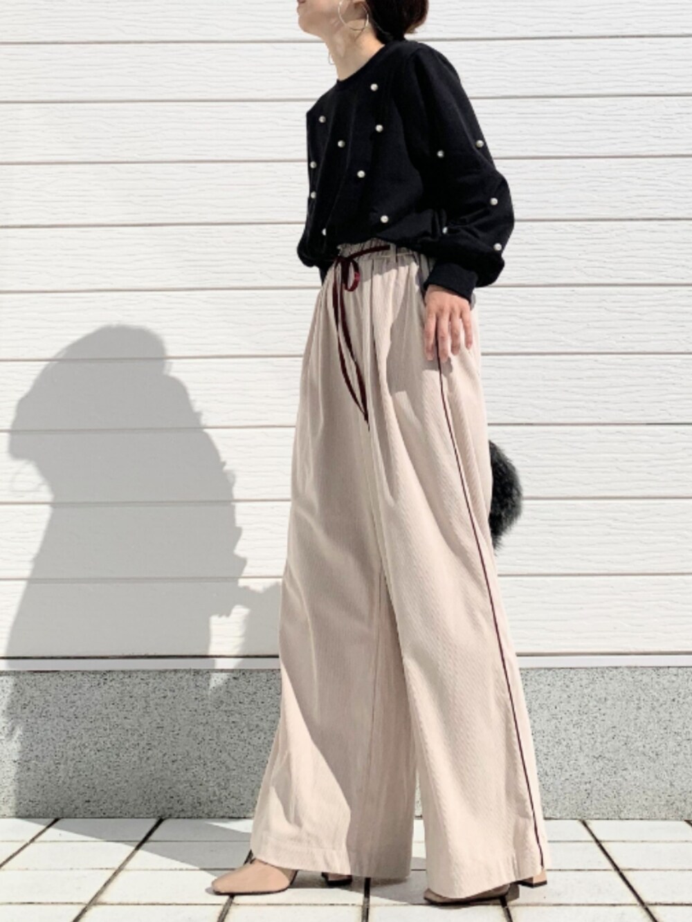 グレー系のハンドバッグ、ブラック系のスウェット、ベージュ系のその他パンツを着用したレディースの秋コーディネートの2枚目の写真