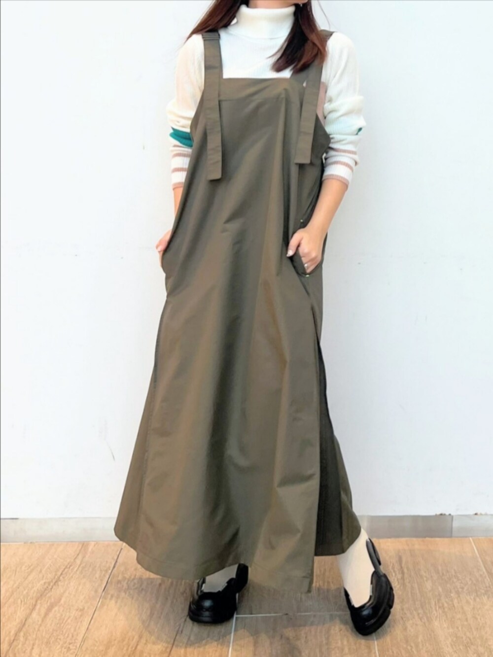 ホワイト系のブーツ、ホワイト系のニット/セーター、グリーン系のワンピースを着用したレディースの冬コーディネートの2枚目の写真