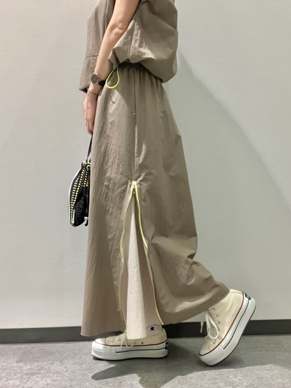 グリーン系のパーカー、グリーン系のスカート、ブラック系のトートバッグを着用したレディースの夏コーディネートの2枚目の写真