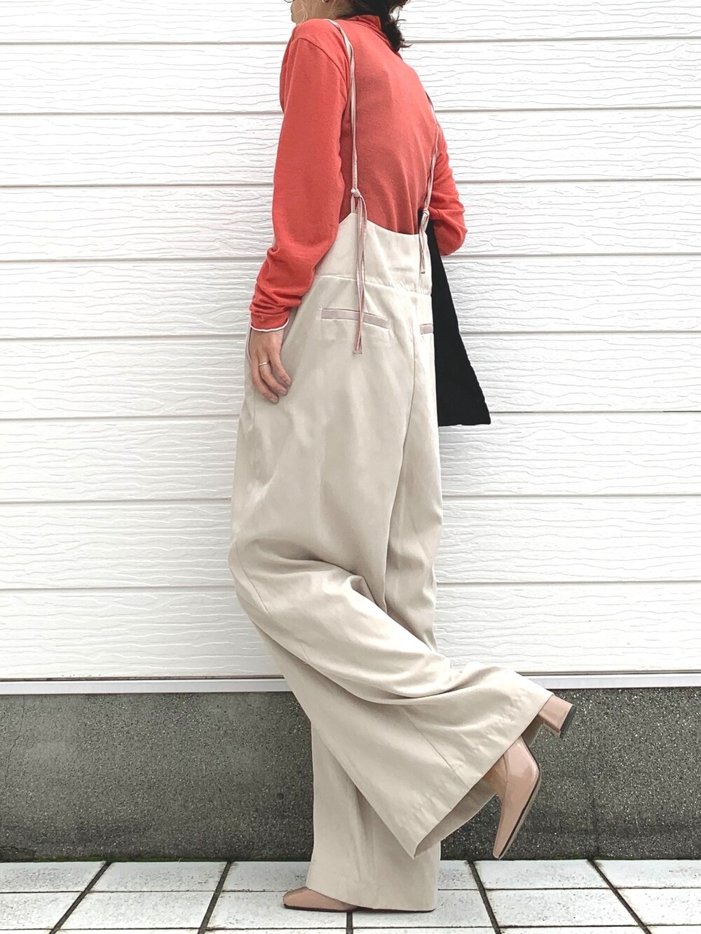 ベージュ系のショルダーバッグ、オレンジ系のTシャツ/カットソー、ベージュ系のサロペット/オーバーオールを着用したレディースの秋コーディネートの2枚目の写真