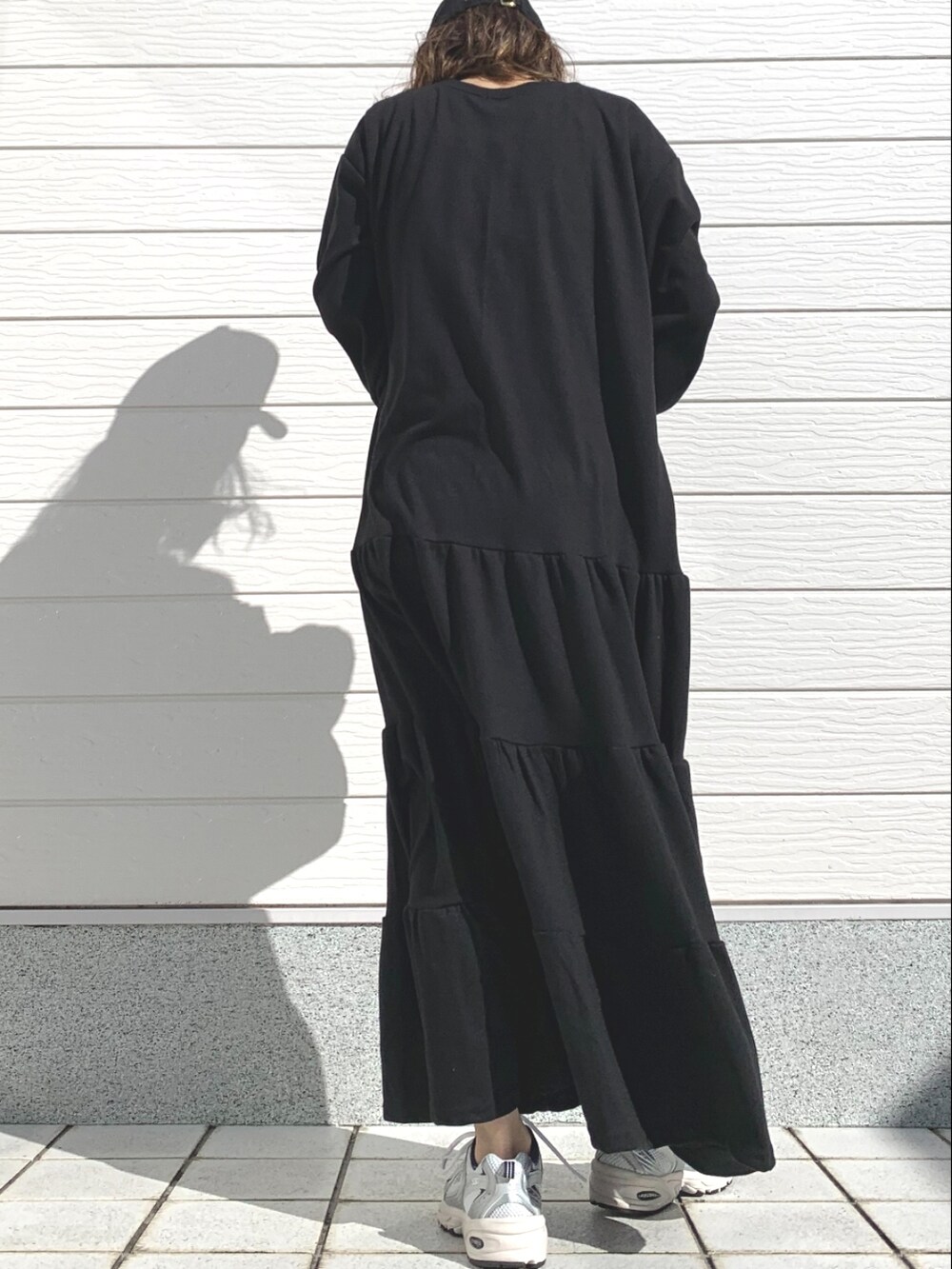 ブルー系のハンドバッグ、ブラック系のワンピース、シルバー系のスニーカーを着用したレディースの冬コーディネートの3枚目の写真