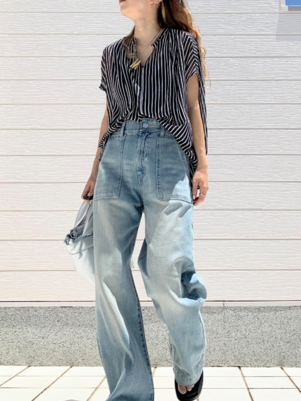 シルバー系のショルダーバッグ、ブルー系のデニムパンツ、ブルー系のシャツ/ブラウスを着用したレディースの夏コーディネートの2枚目の写真