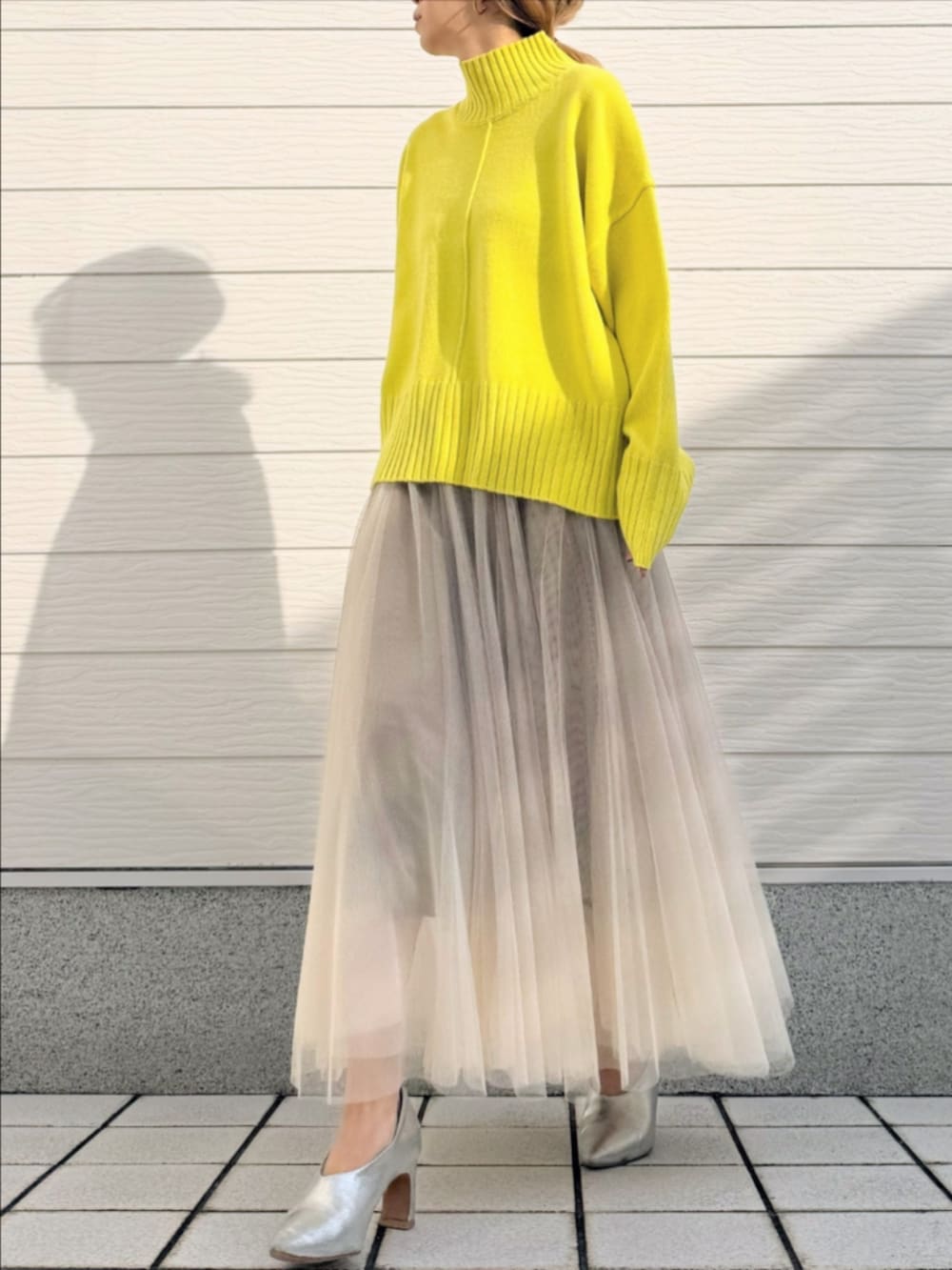 ゴールド系のスカート、グリーン系のニット/セーターを着用したレディースの冬コーディネートの2枚目の写真