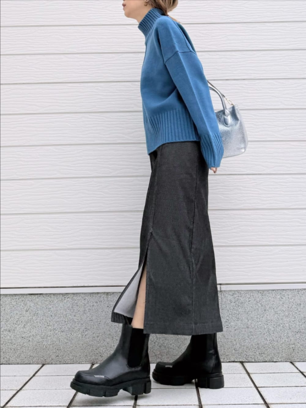 グレー系のスカート、ブラック系のブーツ、シルバー系のトートバッグを着用したレディースの冬コーディネートの2枚目の写真