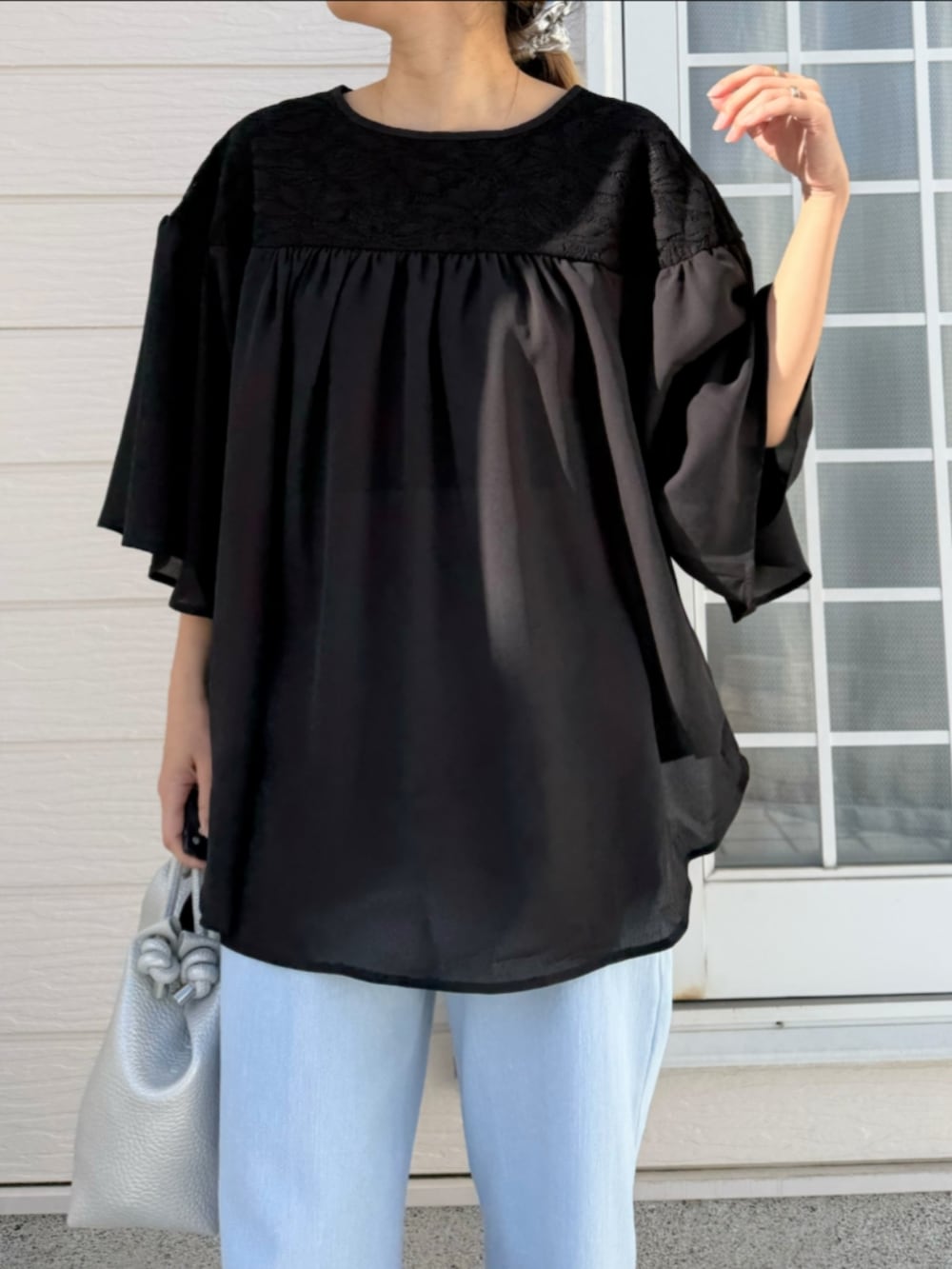 ブルー系のデニムパンツ、シルバー系のトートバッグ、ブラック系のシャツ/ブラウスを着用したレディースの春コーディネートの3枚目の写真