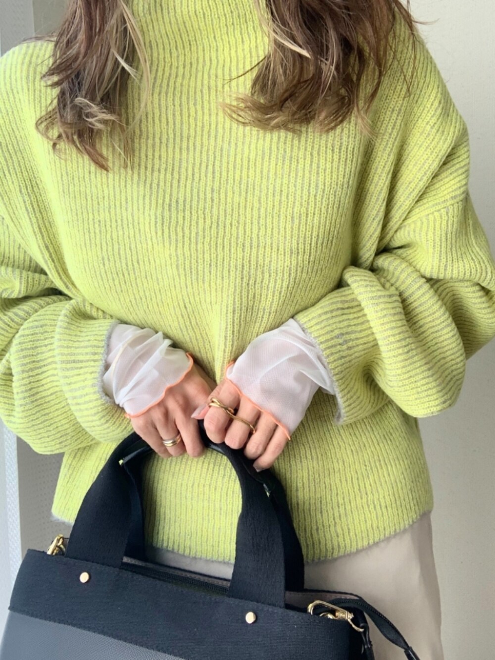 グレー系のニット/セーター、ホワイト系のスカート、ブラック系のトートバッグを着用したレディースの秋コーディネートの4枚目の写真