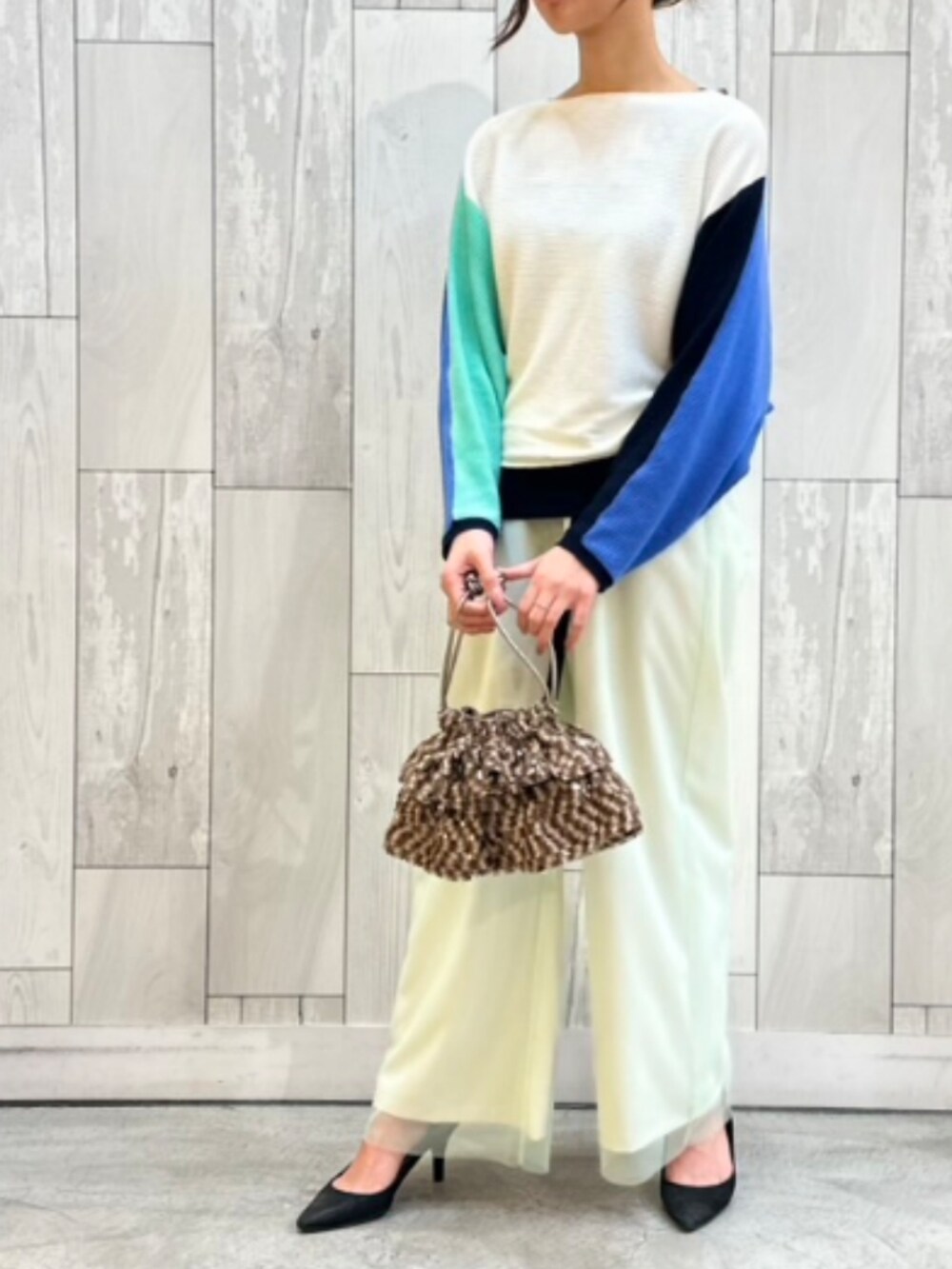 ブラウン系のクラッチバッグ、ベージュ系のその他パンツ、ブルー系のニット/セーターを着用したレディースの冬コーディネートの2枚目の写真