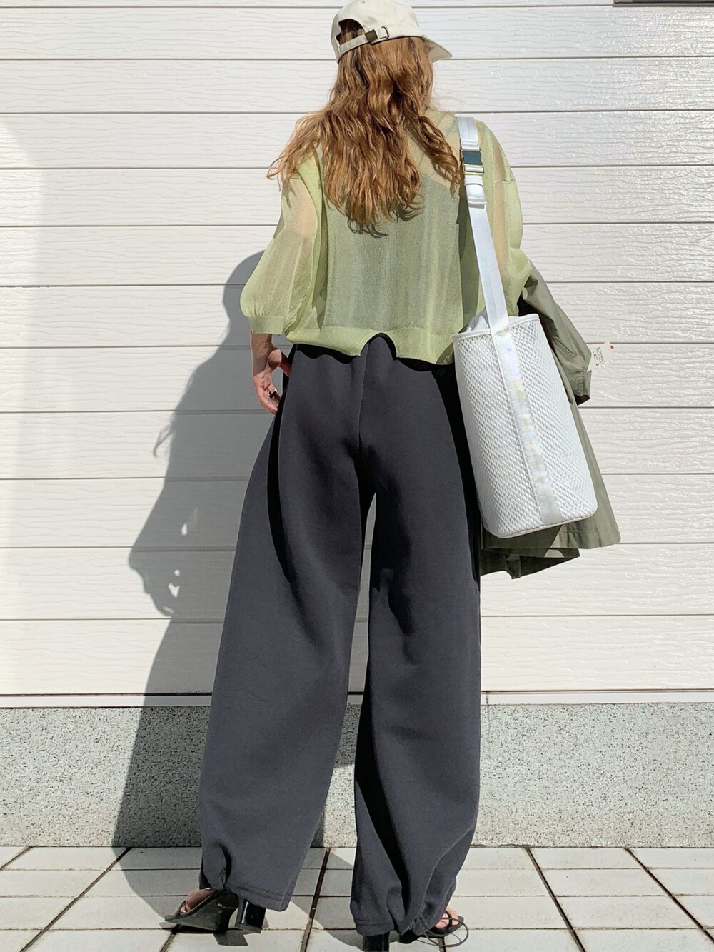 グリーン系のノーカラーコート、グリーン系のニット/セーター、ホワイト系のショルダーバッグを着用したレディースの春コーディネートの3枚目の写真